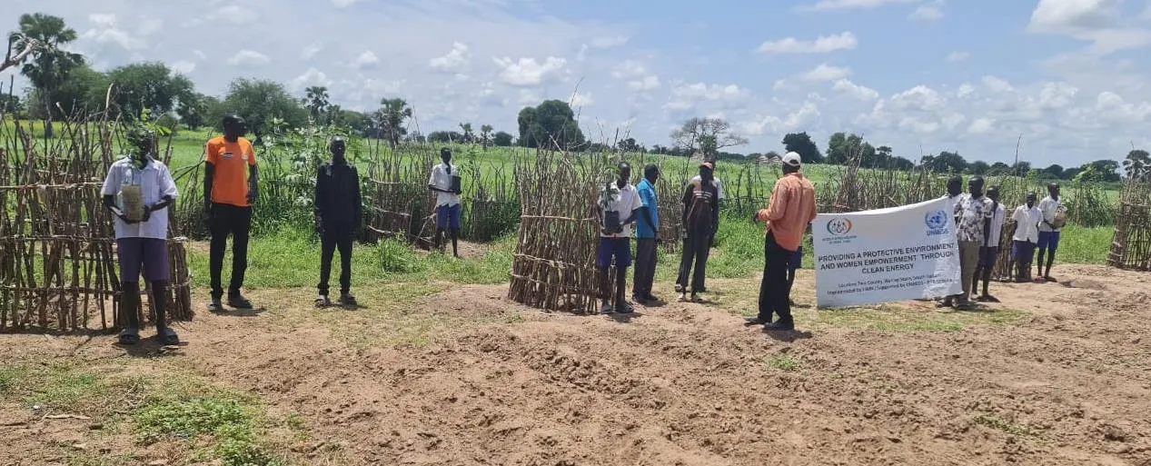 Students and teachers gather at a school restoration site with the project banner.